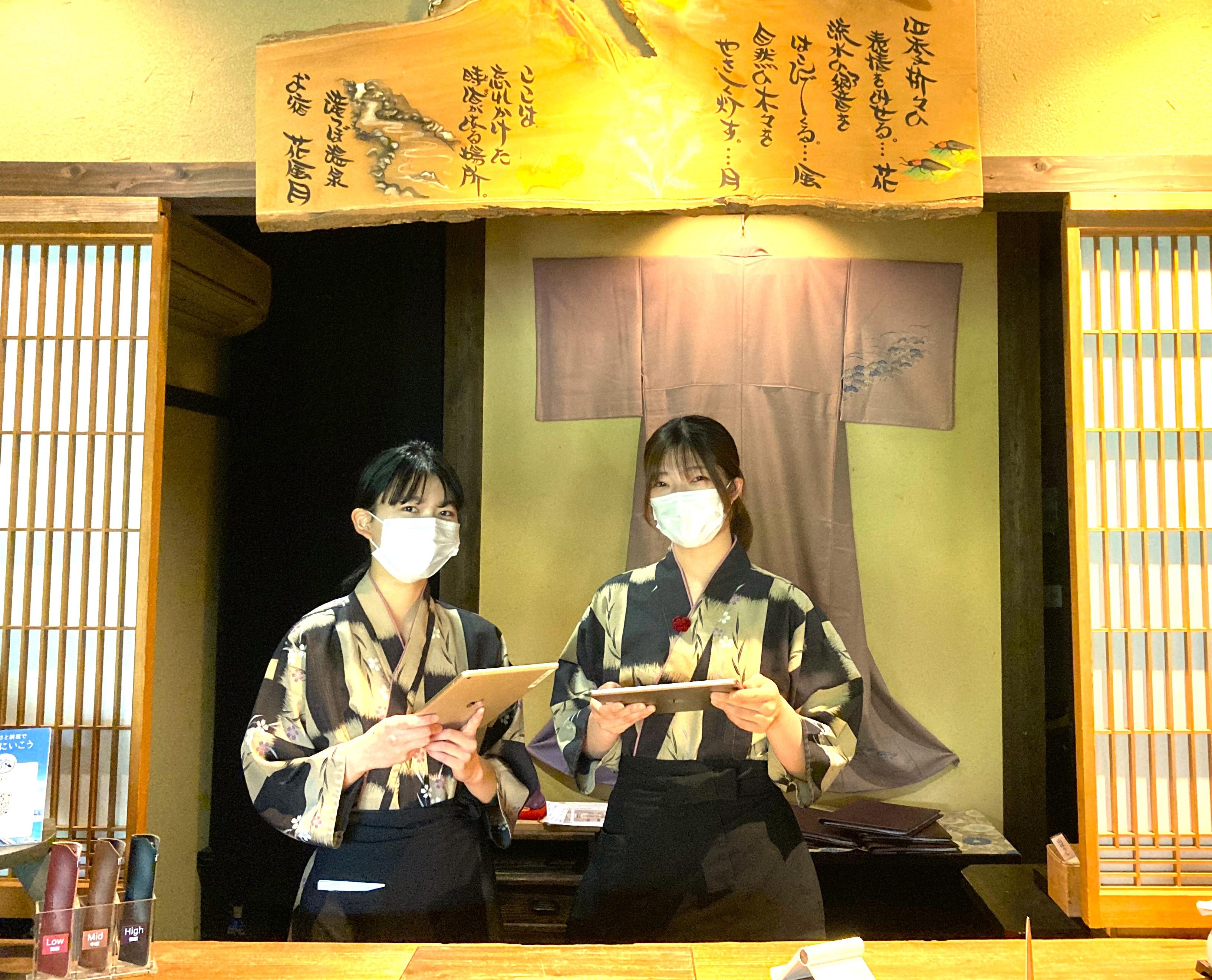 フロントで23歳コンビが決め顔。フロントと仲居を統合しマルチ化を進めつつ、長時間勤務削減を推進中。